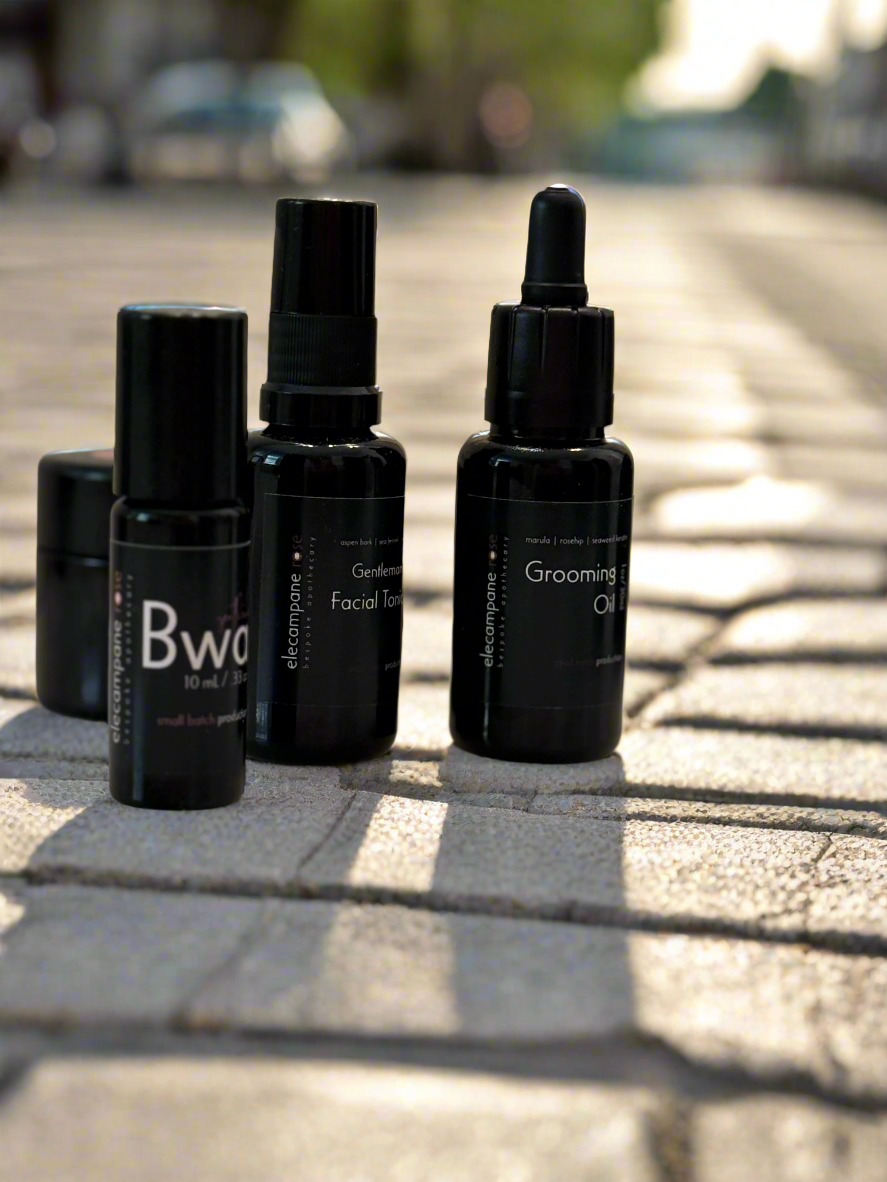 Set of black grooming bottles on a stone pavement