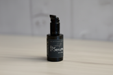 Black serum bottle with label on a neutral background